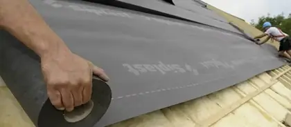 Déroulage d'une membrane d'étanchéité sur toiture