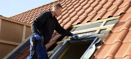 Couvreur posant une fenêtre de toit sur une couverture en tuiles
